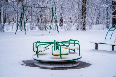 Bir kış günü Ukrayna 'da şehir parkında temiz karla kaplanmış bir çocuk parkında sallanıyor.
