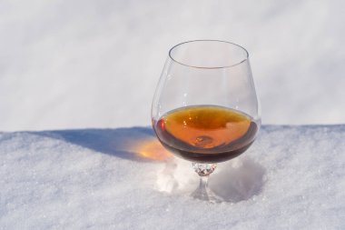 Kar yatağında bir bardak konyak ve beyaz arka plan, yakın çekim. Noel kış sabahı kavramı