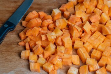 Bıçak ve taze havuç dilimleri bir masanın üzerindeki kesme tahtasında, yakın çekim.