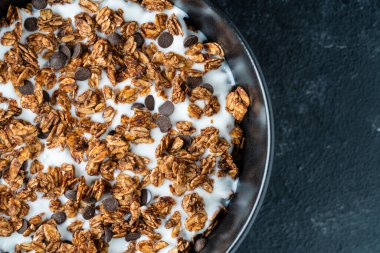 Yulaf ezmeli granola, kurutulmuş meyve, bal, kuru üzüm, çikolata cipsi, badem ve yoğurtlu fındık, yakın çekim, üst manzara. Sağlıklı kahvaltı kavramı