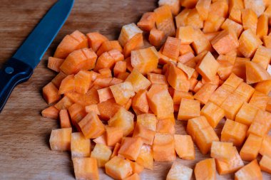 Bıçak ve taze havuç dilimleri bir masanın üzerindeki kesme tahtasında, yakın çekim.