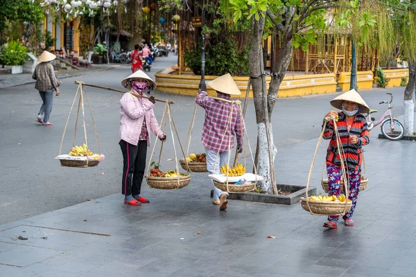 ホイアン ベトナム 2020年3月16日 ベトナムホイアンの古い黄色の壁を背景に 旧市街の路上市場で果物のバスケットとわらの帽子のベトナム人女性 — ストック写真