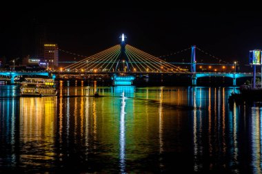 Da Nang, Vietnam - 14 Mart 2020: Geceleyin Danang, Vietnam 'da, nehrin üzerindeki lüks köprü, gece sularını yansıtıyor.