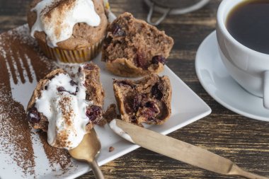 Dondurmalı vişneli kek ve ahşap zemin üzerinde çay olan beyaz kupa.