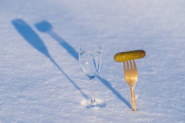 Bir bardak votka ve kışın beyaz kar üzerinde salatalık turşulu bir çatal. Yaklaş, Ukrayna.