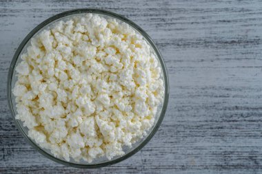 Arka planda cam kase içinde süzme peynir, üst manzara. Süt ürünlerinin beyaz taneli dokusu, süzme peynir, yakın çekim. Süt ürünü konsepti