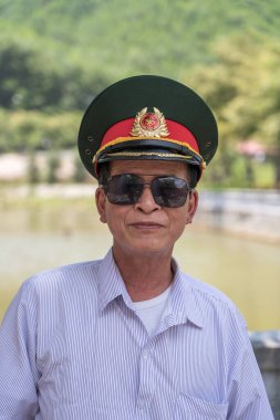 Danang, Vietnam - 27 Haziran 2020: kafasında askeri şapkası ve sokaklarda güneş gözlüğü olan Vietnamlı mutlu adam Da Nang, Vietnam