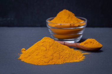 Organik zerdeçal, siyah tabakta sokağa çıkma yasağı tozu. Köri tozu. Kapat.