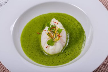 Yerel malzemelerle yemek pişirmek - haşlanmış yumurta ve yeşil sağlıklı sos, beyaz tabağa yakın.