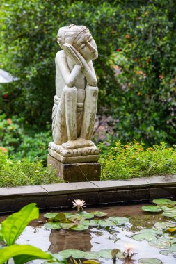 Tropikal bahçedeki göletin yanında geleneksel bale taş heykeli. Bali Adası, Ubud, Endonezya