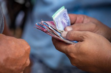 Endonezya kağıt parasıyla el ele tutuşan adam, Bali, Endonezya. Endonezya Rupisi