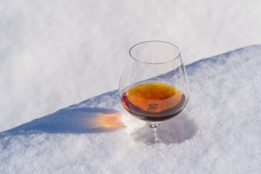 Kar yatağında bir bardak konyak ve beyaz arka plan, yakın çekim. Noel kış sabahı kavramı