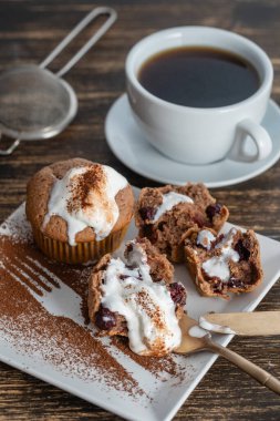 Dondurmalı vişneli kek ve ahşap zemin üzerinde çay olan beyaz kupa.