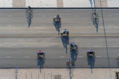 Nha Trang, Vietnam - 21 Nisan 2020: Nha Trang, Vietnam 'da deniz kenarında bir sahil yolunda sabah trafiği. Gün doğumunda motosikletlerin önünden geçmesinin gölgesi, hava manzarası