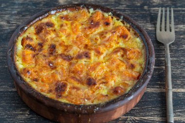 Süt soslu fırında sarı balkabağı. Tahta masadaki bir tabakta bal ve yumurta. Vejetaryen yemeği, Ukrayna, yakın çekim.