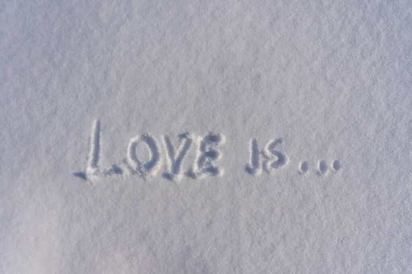 Text love is on a white fresh snow in winter, close up. Winter love symbol as a romance shape greetings, copy space background