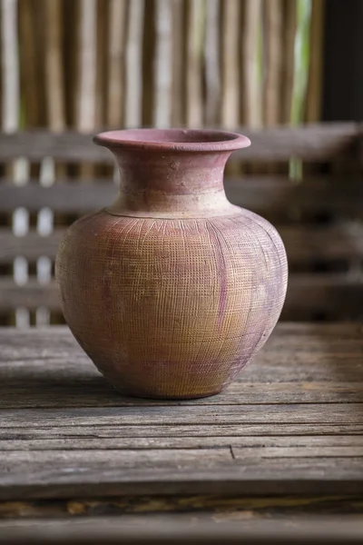 Old clay vase of manual work on wooden table in thai home, close up