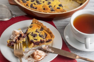 Dondurmalı taze vişneli turta ve ahşap zemin üzerinde çay olan beyaz bardak.