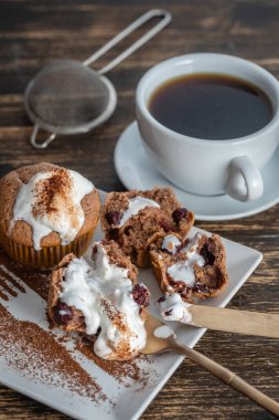 Dondurmalı vişneli kek ve ahşap zemin üzerinde çay olan beyaz kupa.