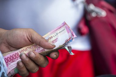 Endonezya kağıt parasıyla el ele tutuşan adam, Bali, Endonezya. Endonezya Rupisi