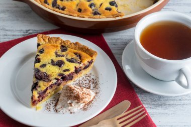 Dondurmalı taze vişneli turta ve ahşap zemin üzerinde çay olan beyaz bardak.