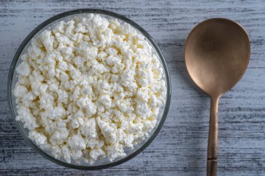 Arka planda cam kase içinde süzme peynir, üst manzara. Süt ürünlerinin beyaz taneli dokusu, süzme peynir, yakın çekim. Süt ürünü konsepti