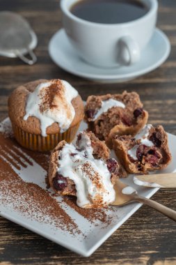 Dondurmalı vişneli kek ve ahşap zemin üzerinde çay olan beyaz kupa.