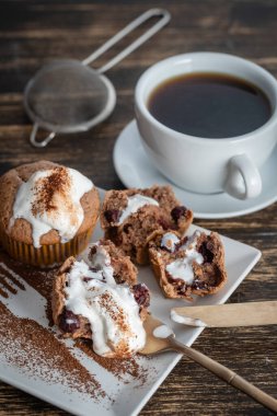 Dondurmalı vişneli kek ve ahşap zemin üzerinde çay olan beyaz kupa.