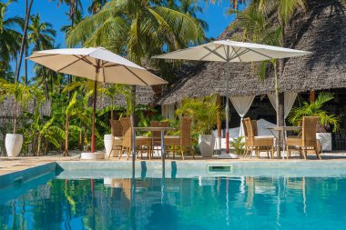 Tanzanya 'daki Zanzibar Adası' ndaki yüzme havuzunun yanındaki boş kafede masa ve sandalyeler. Seyahat ve tatil kavramı
