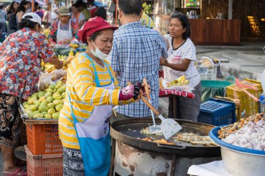 Koh Phangan, Tayland - 08 Şubat 2020: Tayland sokak satıcısı kadın Koh Phangan, Tayland 'daki geleneksel sokak pazarında yiyecek hazırlıyor ve satıyor