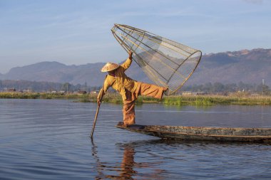 Inle Gölü, Myanmar, Burma - 14 Ocak 2016: Bambu teknesinde Birmanyalı balıkçı el yapımı ağla geleneksel balık yakalıyor. Inle Gölü, Myanmar, Burma