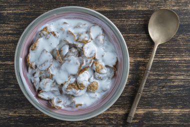 Tam tahıllı gevrek ve yoğurt tabağı, yakın çekim, üst manzara. Sağlıklı kahvaltı, bir kâse dolusu müsli.