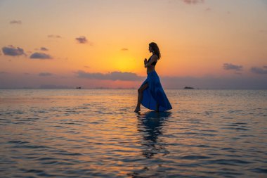 Gün batımında, Tayland 'daki cennet adasında tropikal sahilde dans eden genç bir kız. Yaz kavramı. Tatil seyahati.