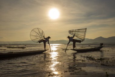 Inle Gölü, Myanmar, Burma - 14 Ocak 2016: Bambu teknesinde Birmanyalı balıkçı el yapımı ağla geleneksel balık yakalıyor. Inle Gölü, Myanmar, Burma