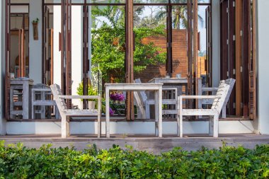 Denizin yanındaki boş sahil kafesinde tahta masa ve sandalyeler. Yaklaş Tayland.