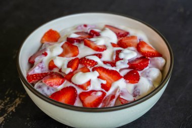 Kırmızı çilek ve beyaz yoğurt. Kahvaltıda meyveli tatlı ve mükemmel olgunlukta çilek, yakın çekim.