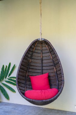 Hasır salıncak, Tayland 'daki Koh Phangan adasında taş duvarın yanında asılı kırmızı bir yastıkla. Kapat.