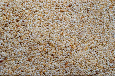 Granola bar. Sağlıklı tatlı atıştırmalığı. Arkaplanda bal olan beyaz susam tohumları, yakın plan, üst görünüm