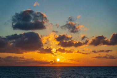 Tayland 'daki Koh Phangan adasında deniz suyunun üzerinde güzel bir günbatımı. Seyahat ve doğa kavramı. Akşam gökyüzü, bulutlar, güneş ve deniz suyu