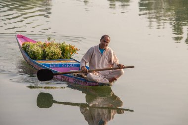 Srinagar, Hindistan - Haziran 07, 2015: Dal Gölü 'nde yaşam tarzı, Hindistan' ın Srinagar, Jammu ve Kashmir eyaletlerinde küçük bir taşımacılık teknesi olan Shikara 'yı kullanır. Hintli adam çiçek satıyor.