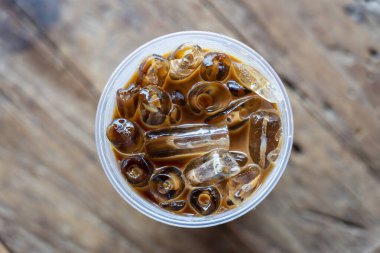 Buzlu kahve ya da ahşap arka planda sütlü kahve. Plastik bardakta buzlu sade kahve.