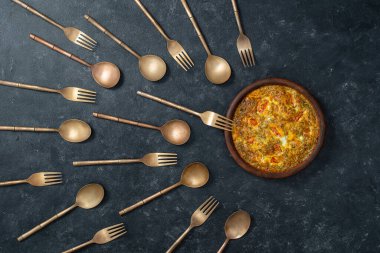 Sebzeli frittata, pirinç çatal ve kaşıklarla seramik kase sperm yarışmasına benziyor. Spermatozoonlar yumurtaya doğru yüzüyor. Döllenme, hamilelik ve doğum kontrolü kavramı. Üst görünüm, kapat