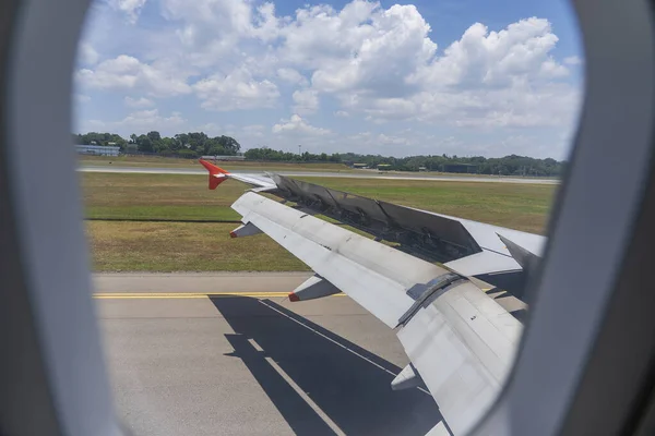 An airplane window view of wing and flaps after landing. Landing aircraft at the airport. Braking of the aircraft on the runway, wing of the plane is in working order. View from window. Close up shot