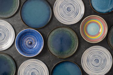 Siyah zemin üzerinde bir sürü renkli boş seramik plaka, kapatın. Yukarıdan görüntüle