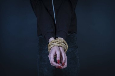 Siyah arka planda elleri bağlı genç bir kız. Kadın şiddeti kavramı. Kapat.