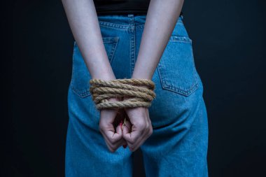 Siyah arka planda elleri bağlı genç bir kız. Kadın şiddeti kavramı. Kapat.