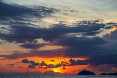 Tayland 'daki Koh Phangan adasında deniz suyunun üzerinde güzel bir günbatımı. Seyahat ve doğa kavramı. Akşam gökyüzü, bulutlar, güneş ve deniz suyu