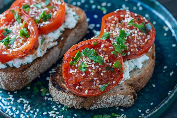ローストレッドトマトとおいしいトーストパン フェタチーズ プレート上のゴマやハーブ クローズアップ — ストック写真