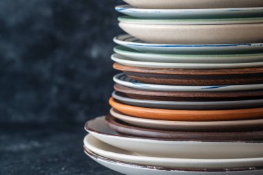 Siyah arkaplanda birçok renk boş seramik plaka, kopyalama alanı, kapat. Koyu arkaplanda yığılmış çeşitli yemekler