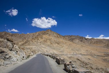 Himalayalar 'da asfalt yol ve Ladakh bölgesinde mavi gökyüzünde beyaz bulut, Jammu ve Kashmir eyaleti, kuzey Hindistan
